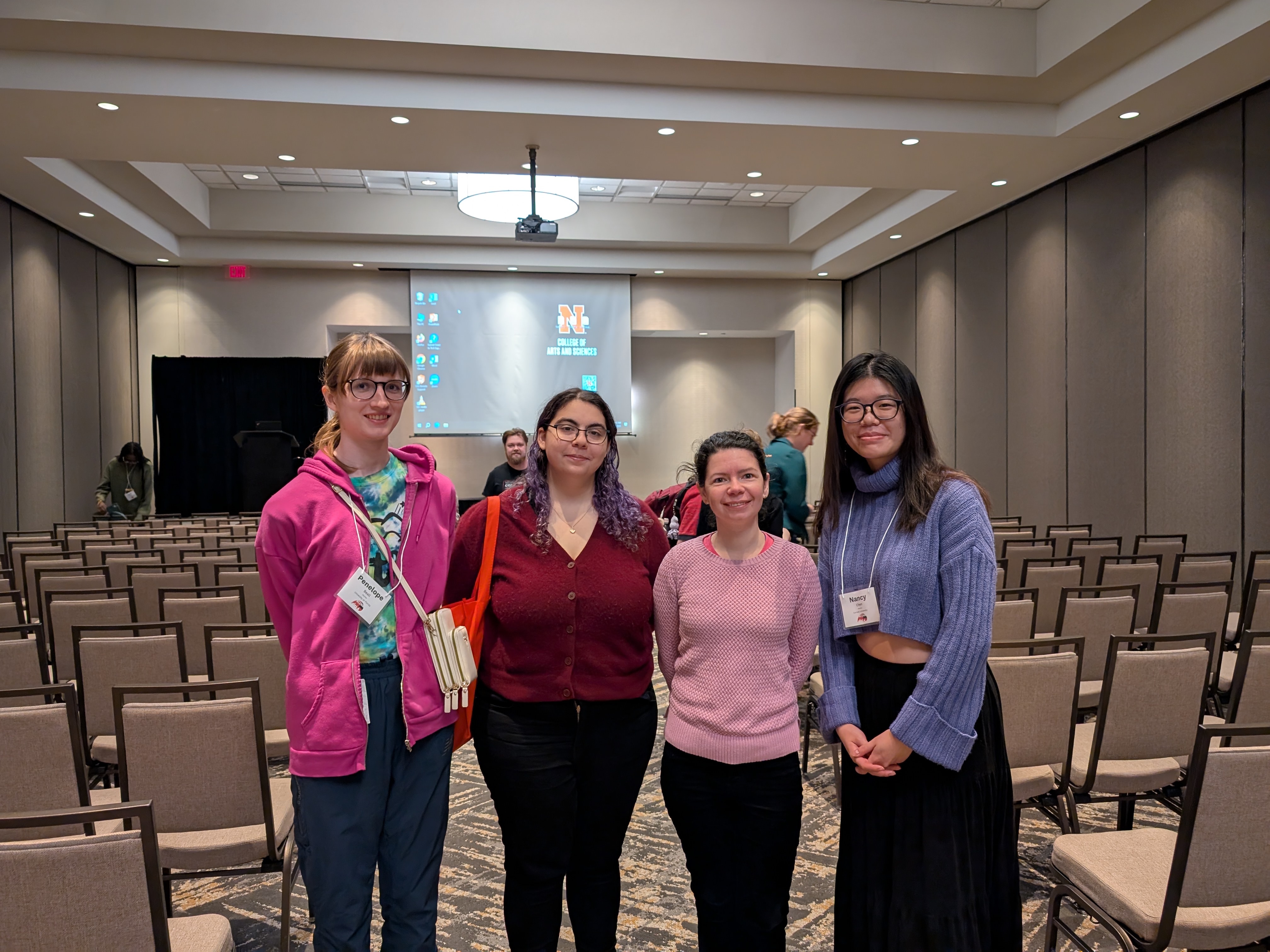 four people standing in a row and looking at the camera